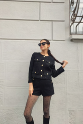 a lady wears a black tweed jacket with matching shorts